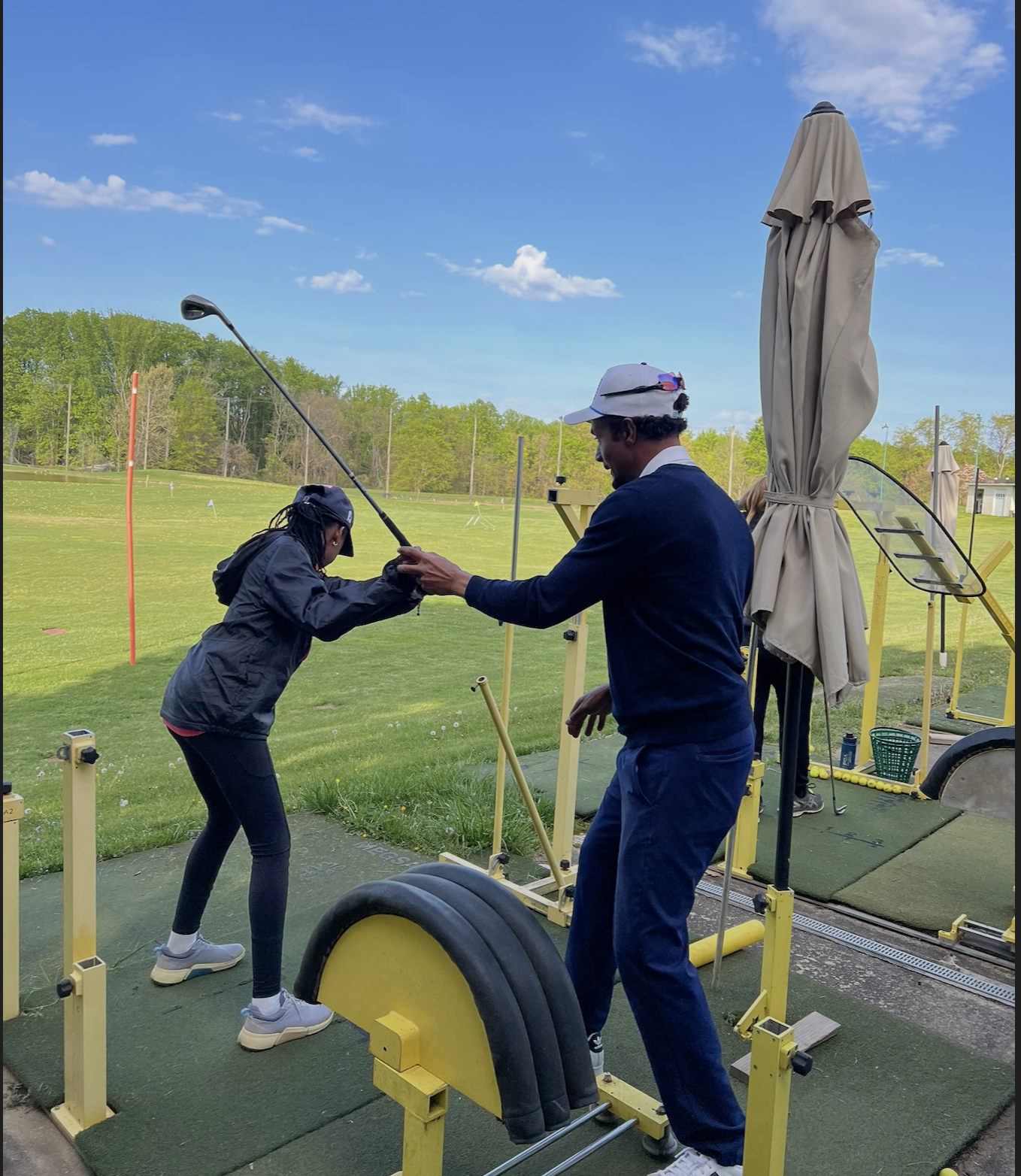 Keith Robertson, PGA Professional, guiding a junior student through a golf swing on the Olney Golf Park driving range with MEGSA training equipment